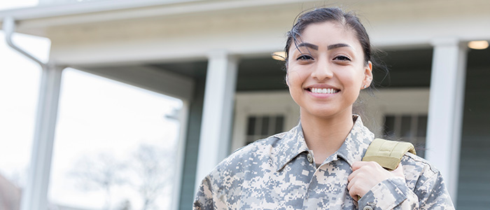 woman in a military uniform standing in front of a home